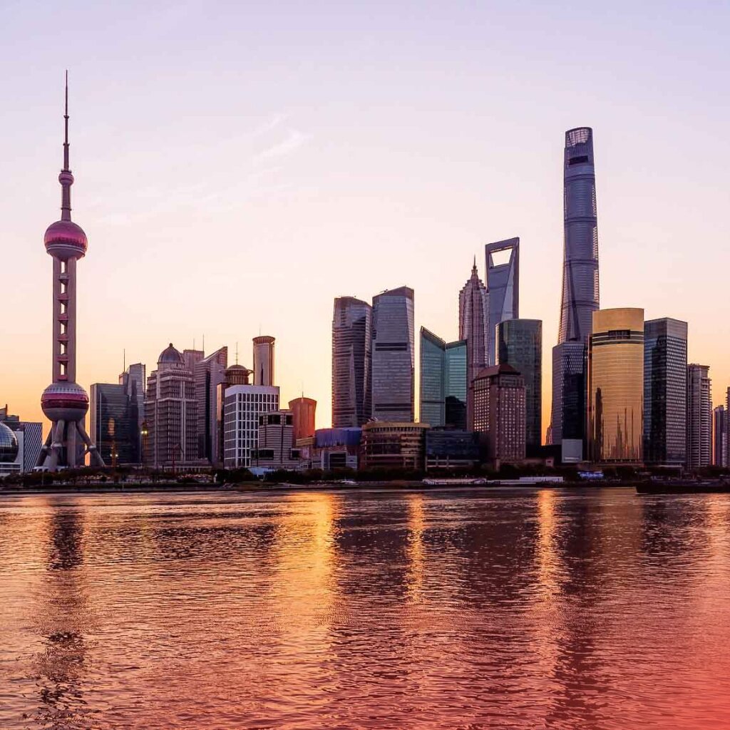 The Shanghai skyline at sunset reflects in the river, symbolising global trade and international business connections.