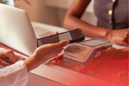 A customer makes a contactless payment with a smartphone at a retail terminal, demonstrating efficient transactions for working capital management.