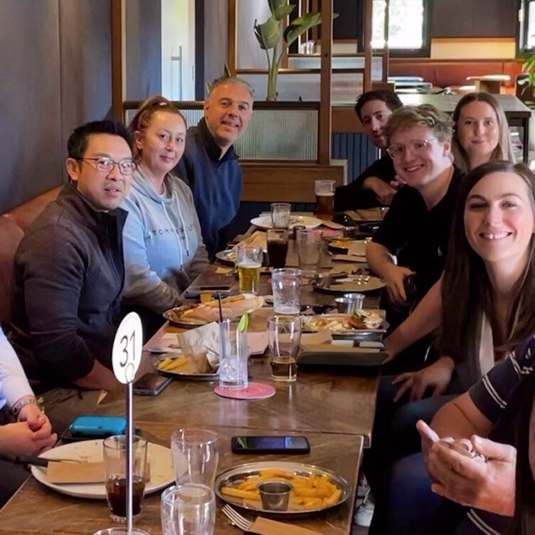 Smiling Octet team members enjoy a social gathering with food and drinks at a restaurant.