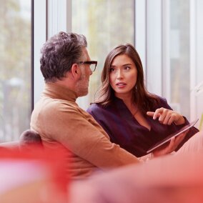 Two business professionals discuss working capital solutions, with the woman pointing at a tablet.
